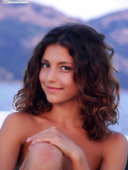 A hot slim brunette with a cute smile sensually takes off her clothes and caresses her soft skin while on a boat trip.